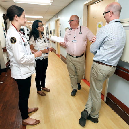 Professor Steyer and students conferring in hallway