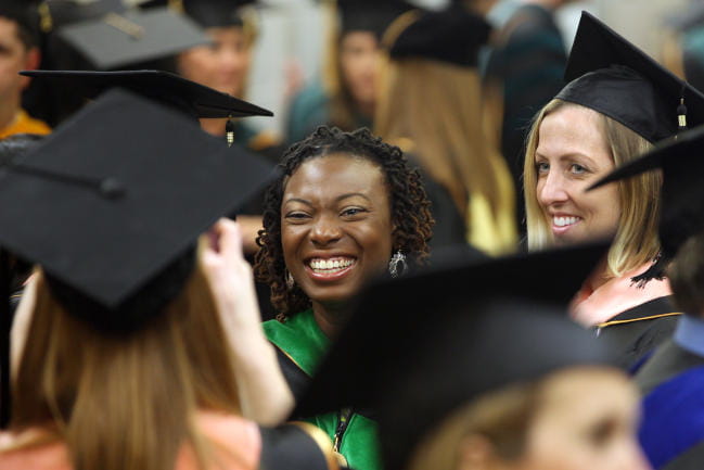 Students in academic regalia smiling during commencement ceremony