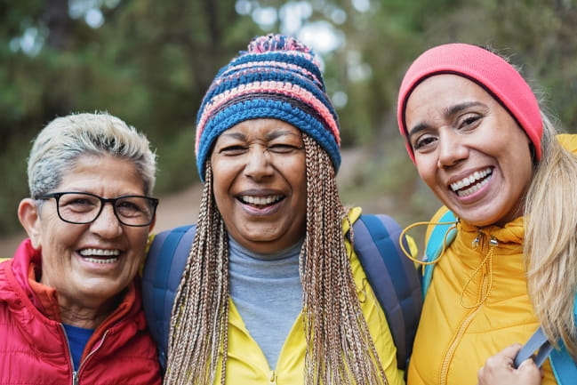 A group of women smile together after a walk on a cold day. 