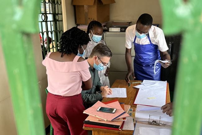 Samuel Kennedy discussing how to properly document study activities with site staff from Makerere University and Kisenyi Health Centre in Kampala, Uganda.