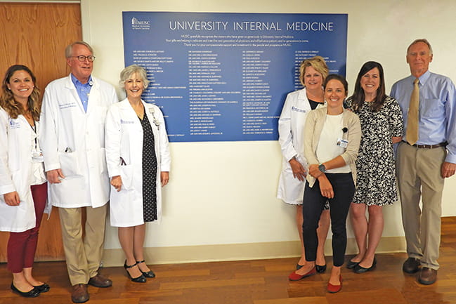 University Internal Medicine staff members gather after the new donor wall is installed in the clinic waiting area.  