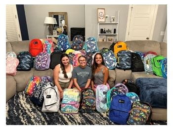 Erica Rubin, Caroline Conroy, and Emilee Young-Rizk with backpacks filled with schools supplies donated during the annual school supplies drive