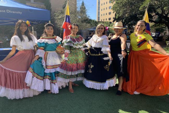 Six women in colorful, native dresses pose for a photo at the 2021 Fiesta Latina
