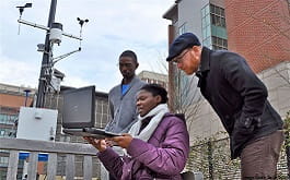 Faculty checking air monitoring site data on a laptop
