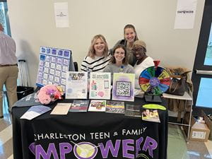 Four team members standing behind a table that displays games and information