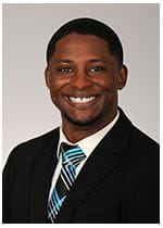 Dr. Donte Bernard is wearing a black suite and is smiling at the camera.