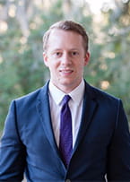 White male with blonde hair standing outside wearing suit.