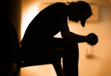 Image of the silhouette of a person hunched over in despair
