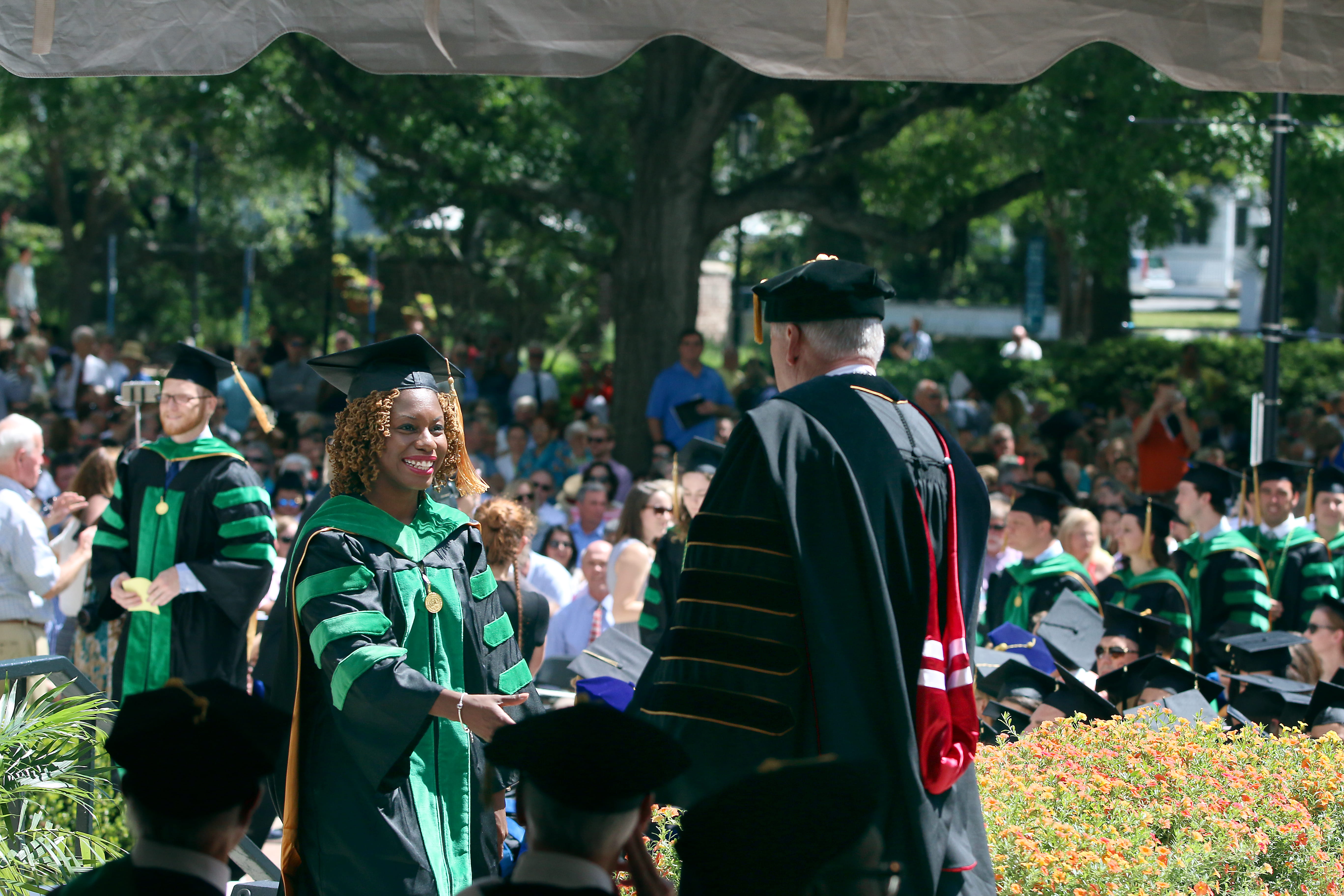Photo of female medical student crossing stage and shaking president's hand at graduation