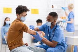 male nurse administering vaccine to male patient