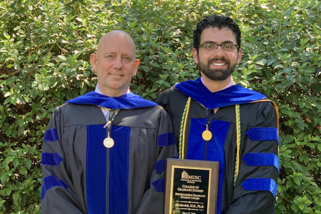 College of Medicine professor and graduate pose with award plaque