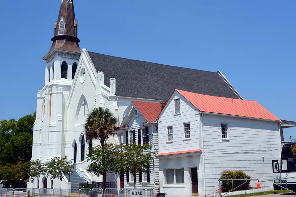 White church next to two houses with reddish roofs.